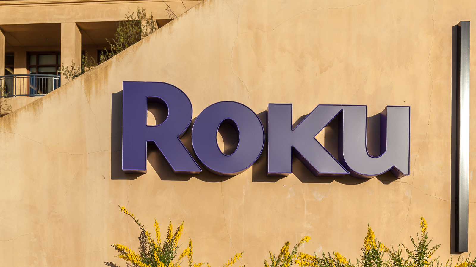 The Roku logo on the side of an office building comprised of sand colored concrete