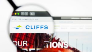 the Cleveland-Cliffs (CLF stock) logo displayed on a web browser and magnified by a magnifying glass