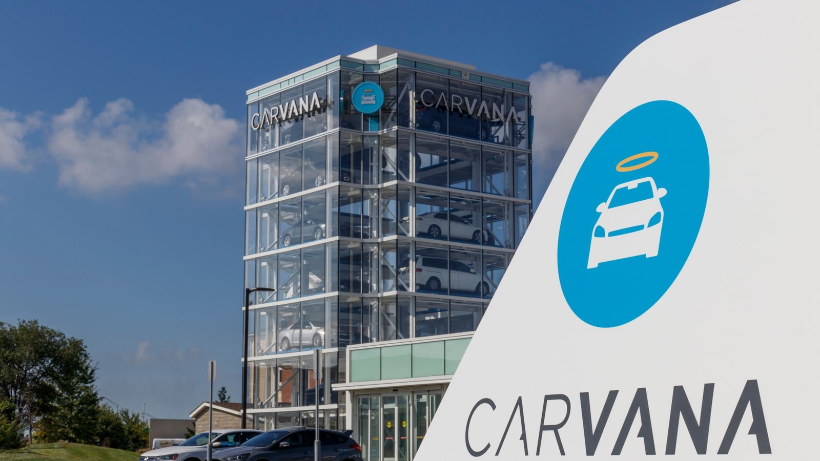 Carvana (CVNA) logo on white object in foreground as well as a high-rise building in the background