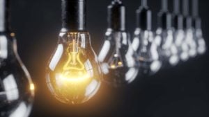 a stock image of light fixtures; one lightbulb is lit up