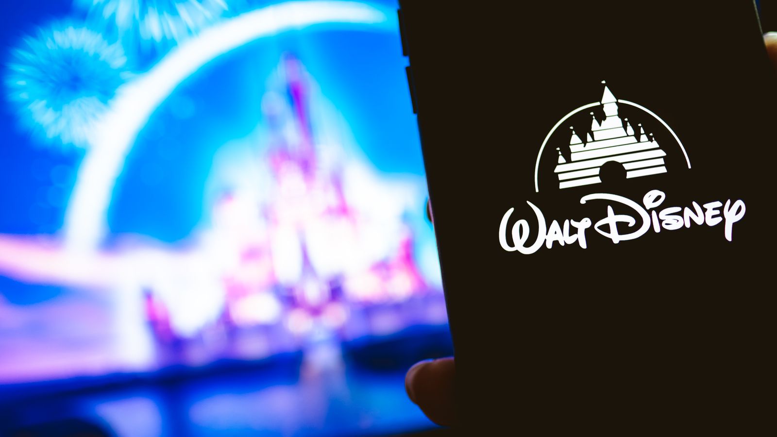 Walt Disney logo on mobile phone with Cinderella's castile in background