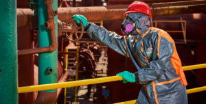 An image of a person in a Hazmat suit turning a handle