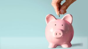 a person putting a coin into a piggy bank