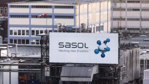 A photo of a billboard on the side of a factory that says "Sasol, reaching new frontiers"