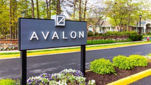 AVB share: an Avalon sign in a garden next to a road