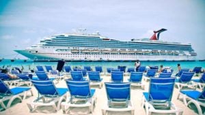 Carnival (CCL) cruise ship on water in front of beach with chairs