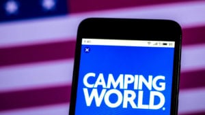 Camping World (CWH) logo on a smartphone in front of an American flag background. hot stocks