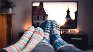 Two pairs of feet in socks in front of a television set