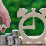 A close-up shot of a hand stacking coins near the outline of a clock. represents long-term stocks to investing for the next decade. safest stocks for portfolio stability. cheap long-term stocks to buy soon