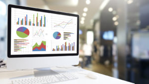 An image of a computer in an office building with several different types of graphs on it. representing artificial intelligence stocks