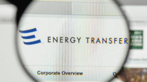 A magnifying glass zooms in on the website for Energy Transfer (ET).