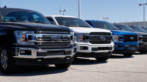 Ford (F) trucks lined up on the lot of a Ford dealership.