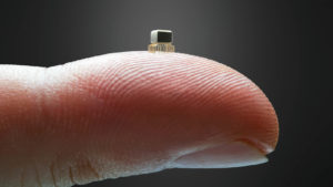 A close-up shot of a microchip on the pad of a finger.