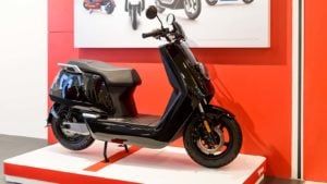 A black Niu branded bike on a white showcase floor contrasted with a red wall