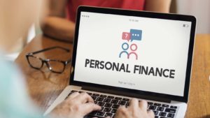 The phrase "personal finance" is displayed on a laptop screen.