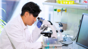 Scientist using a microscope representing OGEN Stock.