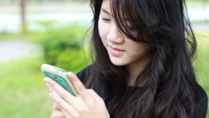 A young woman looks at her smartphone.