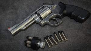 Image of a pistol and several bullets laying on a dark grey surface representing SWBI stock.