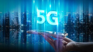 Hologramme numérique 5G flottant au-dessus d'un téléphone sur fond de ville.  représentant 5g d'actions investissant pour la prochaine décennie