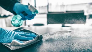 Someone cleaning a kitchen table with a spray bottle and towel representing SNOA stock.