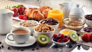A table is spread with breakfast foods like orange juice, berries and croissants. represents food and beverage stocks