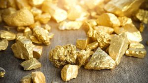 Close up lump of gold mine on wooden table representing gold stocks