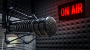 Radio microphone in a soundproofed room with an "on air" sign in the background.