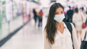 woman in a white shirt wearing a face mask while at an airport representing VRPX Stock.