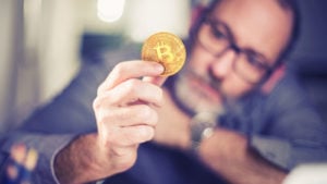 Man holding a physical token representing bitcoin.