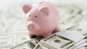 A pink piggy bank sits on top of piles of cash to represent cash-rich stocks