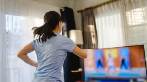 View from behind of woman working out to a televised exercise program.