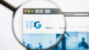 A magnifying glass zooms in on the website of the Interpublic Group of Companies (IPG).