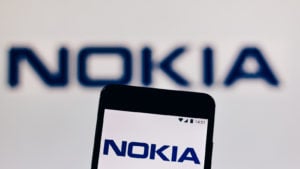 a backdrop featuring the Nokia (NOK) logo with a mobile phone featuring the Nokia logo on its screen in the foreground