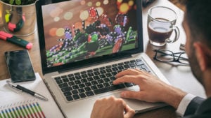 A man looking at a computer with poker chips on the screen.