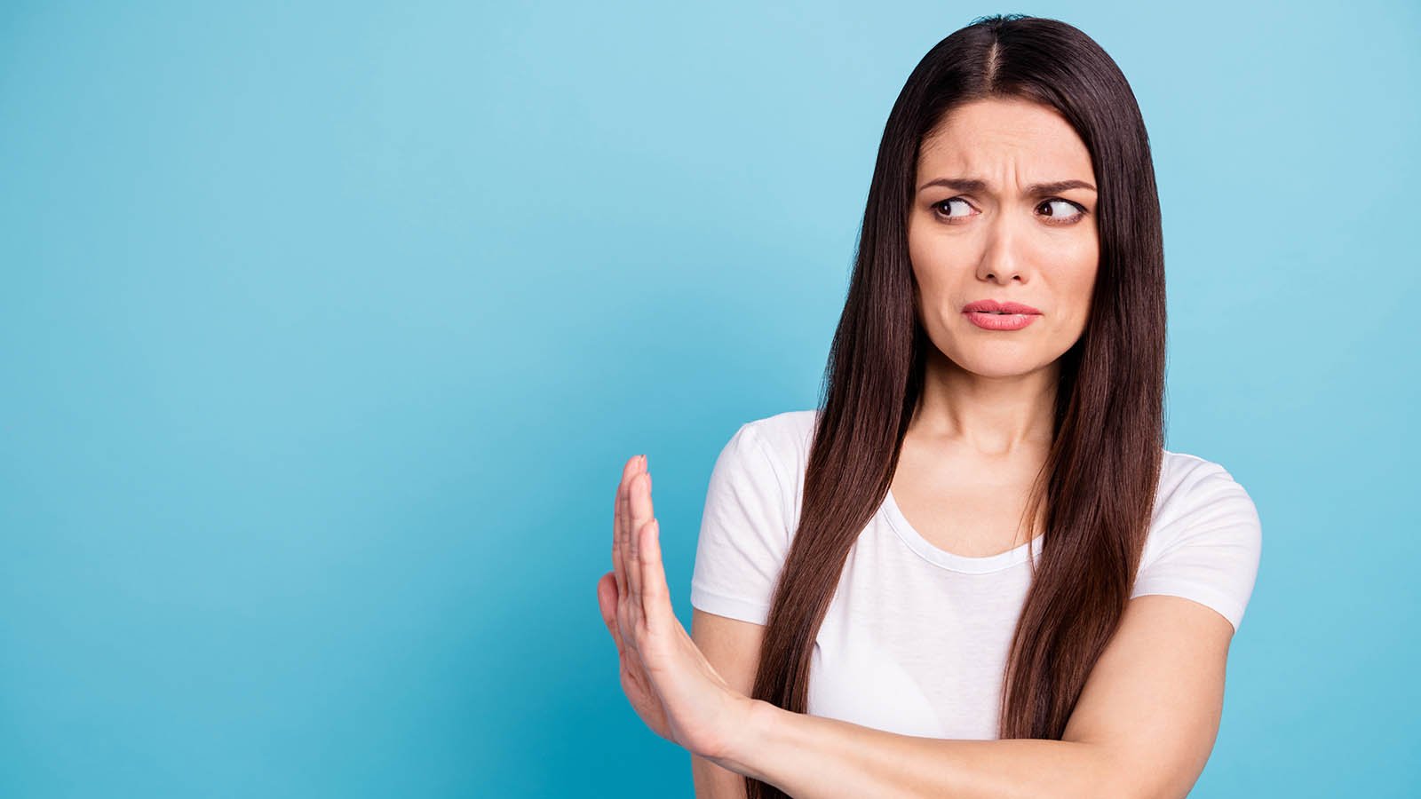 a woman who is frowning and placing her arm up to her side, suggest pushing something away