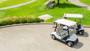 Two golf cars are parked on the green course.
