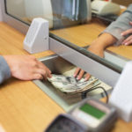bank customer sliding money to teller at bank desk. promising bank stocks