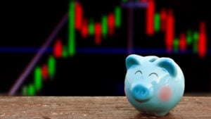 Smiling piggy bank against stock chart background. Represents cheap stocks.
