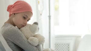 Image of a child cancer patient holding a stuffed bear.