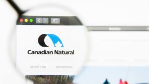 A magnifying glass zooms in on the website for Canadian Natural Resources (CNQ).