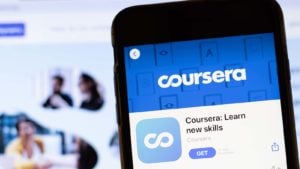 Coursera のアプリ ページはスマートフォンの画面に表示され、背景には Web サイトが表示されます。