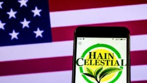 The logo for Hain Celestial (HAIN) displayed on a smartphone screen in front of an American flag.