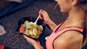 Top view of woman eating healthy food while sitting in a gym