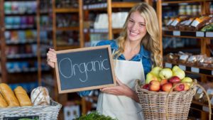 Woman in a market holding sign that reads "Organic"