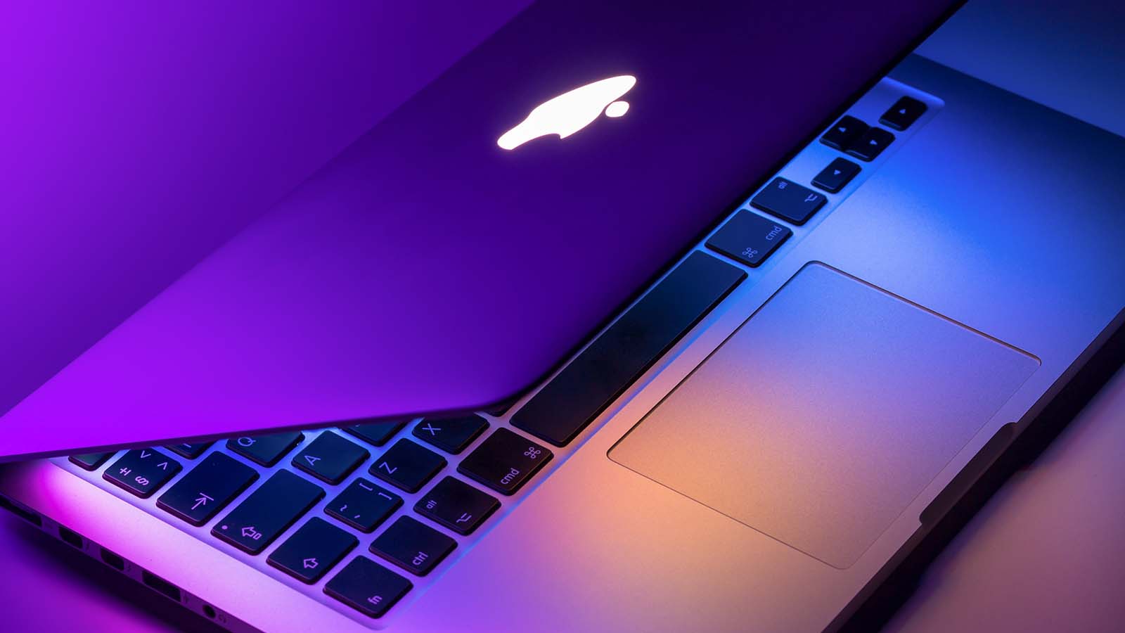 An Apple (AAPL) MacBook Air laptop sitting under bright purple lights.