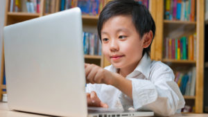 Child pointing at a laptop representing EDU stock.