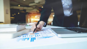 A photo of a businesswoman pointing at charts on a piece of paper on a table.