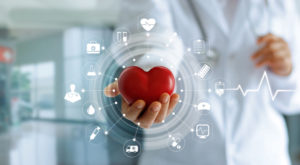 Image of a doctor holding a heart with medical icons surrounding it.