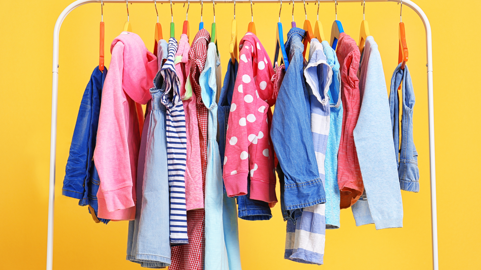 apparel stocks: colorful clothes on a white rack with a bright yellow background