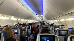 The interior of the Delta Airlines plane is full of passengers. Why are there so many overbooked flights?